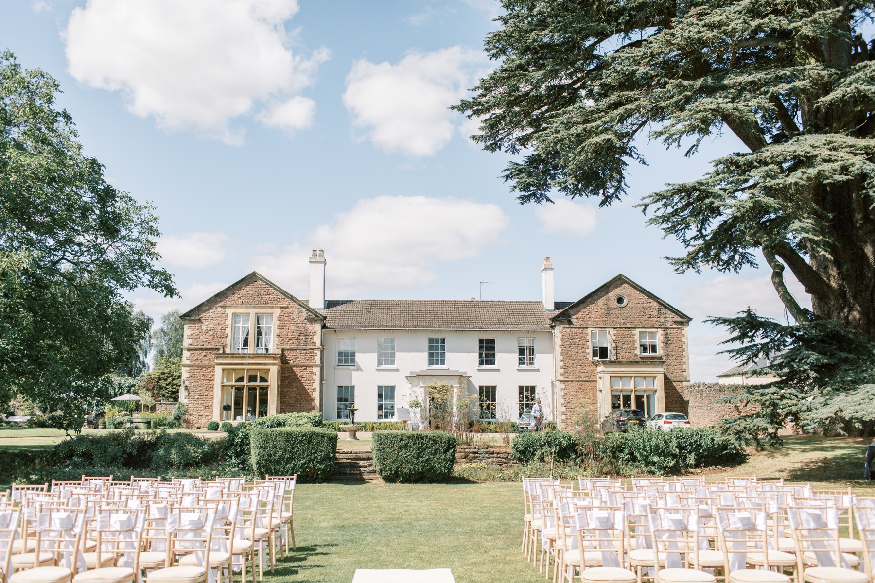 The Glewstone Court manor house with ceremony chairs set on the south lawn beneath the cedar